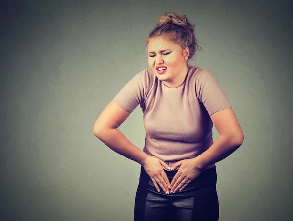 Mujer joven con las manos en el estómago con dolores fuertes dolor. Intoxicación alimentaria, gripe, calambres . —  Fotos de Stock