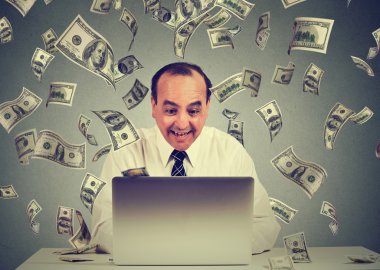 Adam dizüstü bilgisayar bina online iş kullanarak para dolar banknotlar nakit aşağı düşüyor yapma. Para yağmur