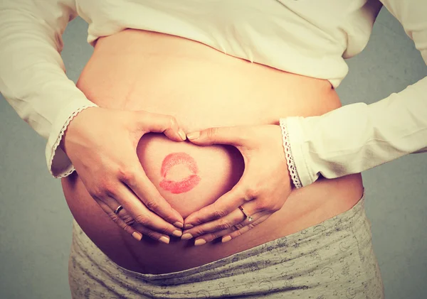 Nahaufnahme eines schwangeren Bauches mit Lippenstift-Zeichen — Stockfoto