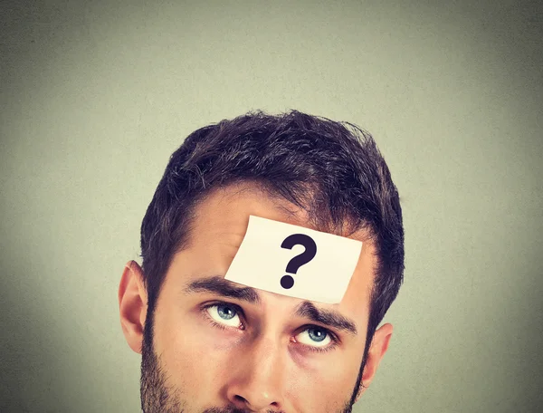Thinking man with question mark on gray wall background — Stock Photo, Image
