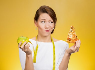 Woman with measuring tape choosing craving slice of pizza instead of green apple 