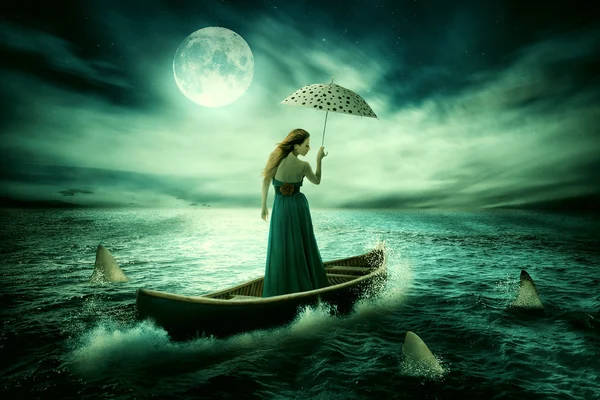 Young lonely woman with umbrella drifting on boat after storm surrounded by sharks — Stockfoto