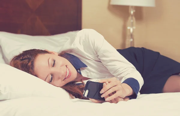 Relajada mujer de negocios leyendo un mensaje de texto en su habitación o habitación de hotel después del trabajo — Foto de Stock