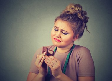 woman with measuring tape tired of diet restrictions craving sweets chocolate