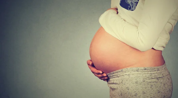 Perfil lateral close-up de uma barriga grávida bonito isolado no fundo da parede cinza com espaço de cópia — Fotografia de Stock