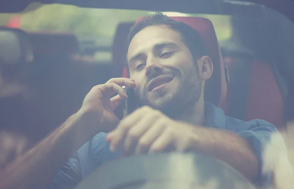 Beau jeune homme parlant sur téléphone portable tout en conduisant sa voiture — Photo