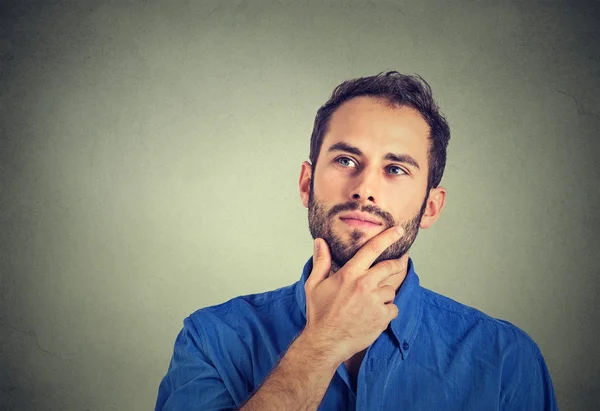 Happy young man thinking daydreaming looking up isolated on gray wall background — Stock Photo, Image