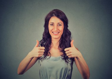 Başparmak yukarı. İş kadını gri duvar arka planında izole edilmiş. Kadın model.