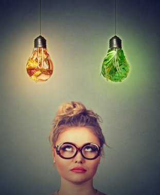 Woman thinking looking up at junk food and green vegetables shaped as light bulb above head 