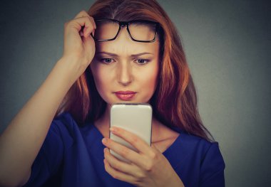 young woman with glasses having trouble seeing cell phone has vision problems