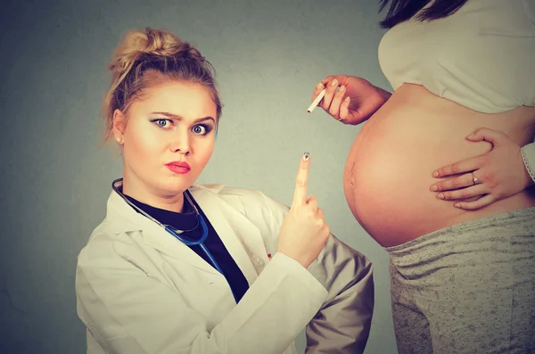 Nahaufnahme verärgerter Arzt zeigt mit Zigarette in der Hand auf Schwangere — Stockfoto