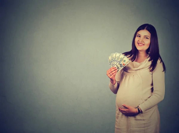 Счастливая беременная женщина с купюрами в долларах наличными — стоковое фото