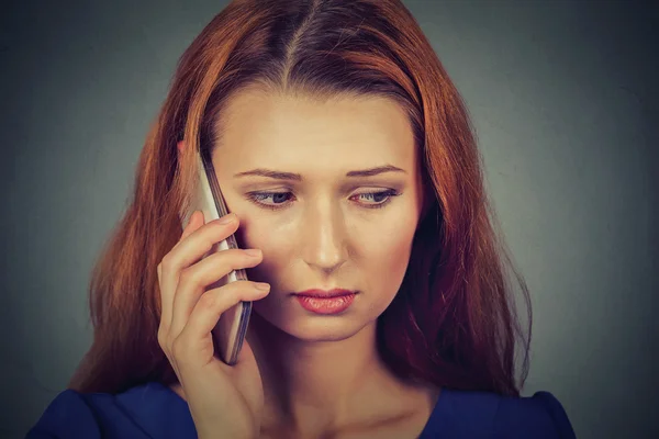 Unhappy young woman talking on mobile phone looking down — Stock Photo, Image