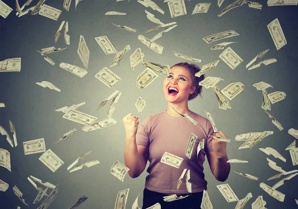 Woman exults pumping fists ecstatic celebrates success under money rain falling down dollar bills banknotes — Stock Photo, Image