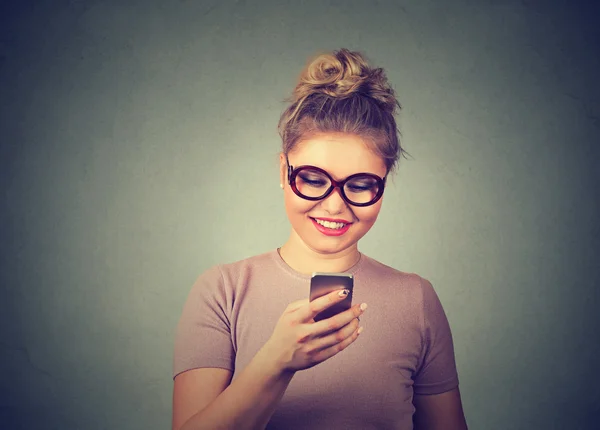 Mujer joven en gafas mensaje de lectura en el teléfono móvil —  Fotos de Stock