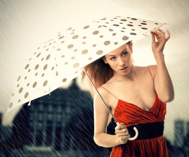 Young woman in red dress with umbrella under rain on night city background