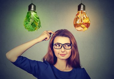 Woman thinking deciding on diet looking up at junk food vegetables light bulbs