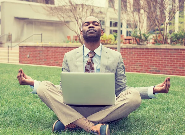 Young businessman with laptop meditating in lotus pose taking a deep breath — ストック写真