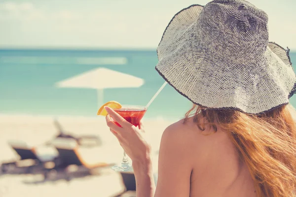 Back View ung kvinna klädd i bikini hålla en cocktail njuter havsutsikt — Stockfoto