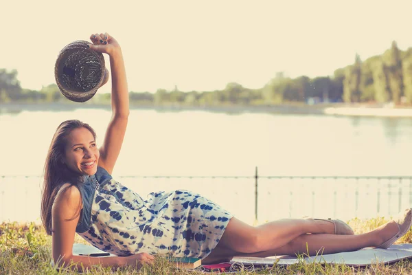 Junge Frau liegt auf einer Wiese vor einem See — Stockfoto