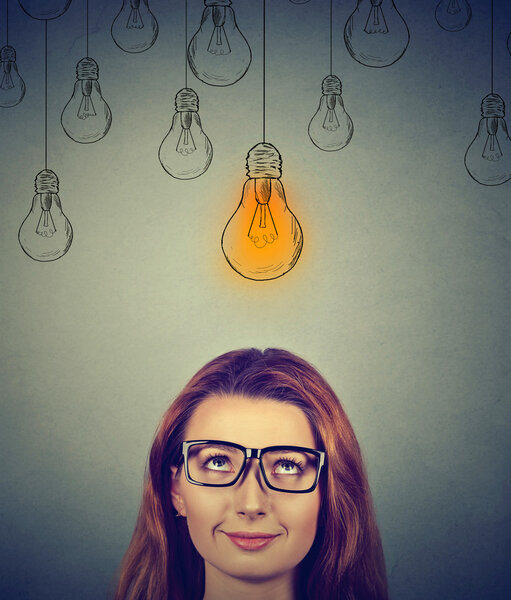 Thinking woman in glasses looking up with light idea bulb above head 