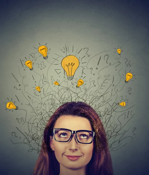 Mulher em óculos com muitas ideias lâmpadas acima da cabeça olhando para cima — Fotografia de Stock