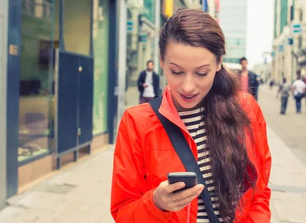 Schöne junge Frau, die auf einer Straße in der Stadt spaziert und ihr Handy benutzt — Stockfoto