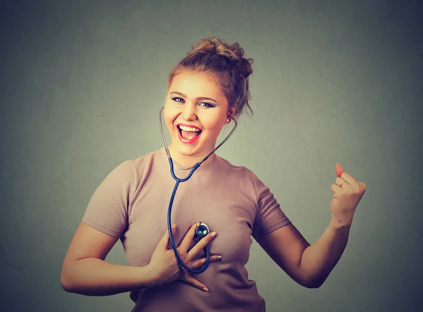 Aufgeregte Frau hört mit Stethoskop auf ihr Herz — Stockfoto