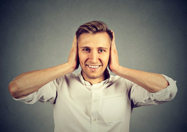 Красивый счастливый молодой человек закрывает уши
 