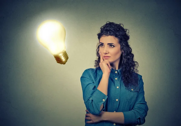 Woman thinking dreaming looking up at bright light bulb — Stock Photo, Image