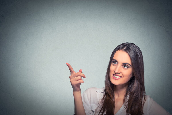 woman looking up pointing with finger at blank copy space 