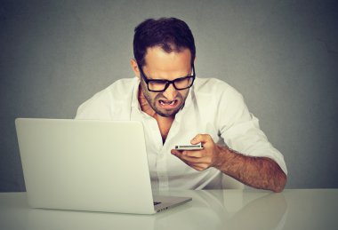 Dizüstü manifatura onun cep telefonu ile sinirli adam 
