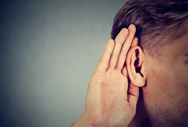 Man holds hand near ear and listens carefully — Stock Photo, Image