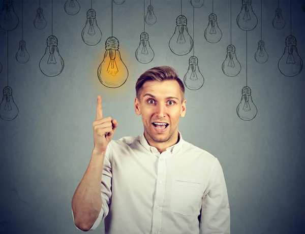 Happy young man pointing at light bulb has a solution — Stock Photo, Image