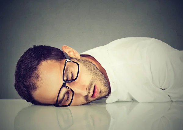 Man met bril slapen op een bureau — Stockfoto