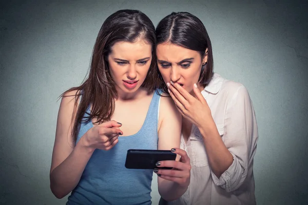 Dos mujeres disgustadas mirando el teléfono móvil — Foto de Stock