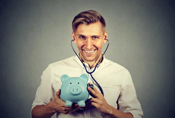 Boldog sikeres ember hallgat malacka bank sztetoszkóppal — Stock Fotó