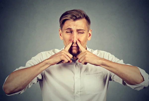 Hombre pellizca nariz miradas con asco algo apesta mal olor — Foto de Stock