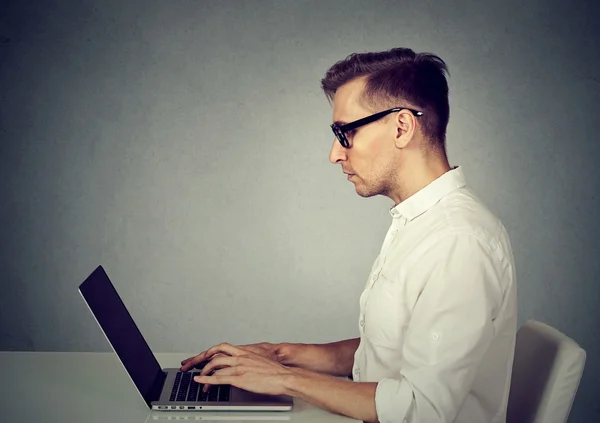 Sida profil ung man använder en bärbar dator — Stockfoto