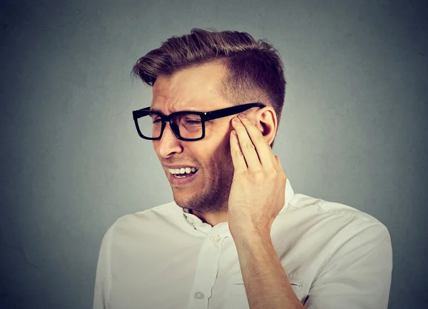 Tinnitus. Sick man having ear pain touching painful head — Stock Photo, Image