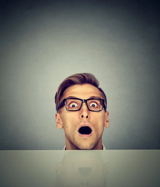 Surprised businessman peeking from under the table — Stock Photo, Image