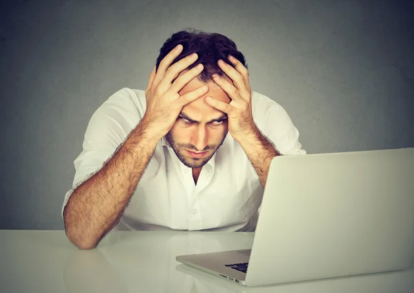 Gestresster junger Mann sitzt am Schreibtisch vor dem Computer — Stockfoto