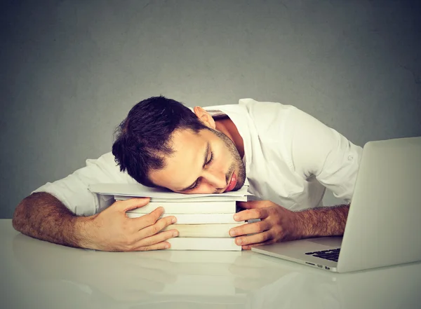 Hombre cansado durmiendo en los libros en su escritorio delante de la computadora —  Fotos de Stock