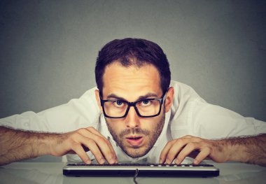 Crazy looking nerdy man typing on the keyboard clipart
