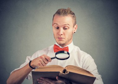 Büyüteçle ilginç bir kitap okuyan genç bir adamın portresi. 