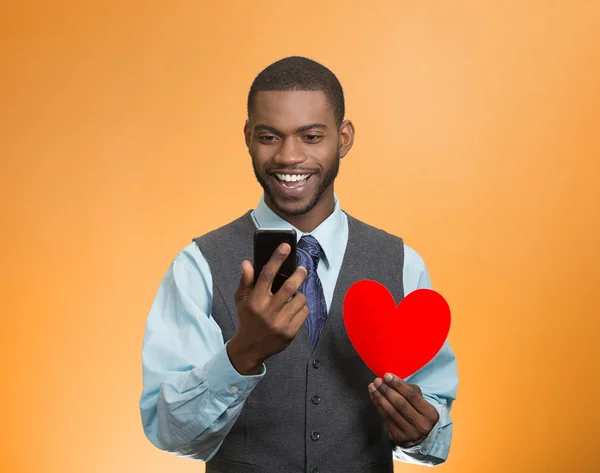Человек проверяет свой смартфон, держит красное сердце — стоковое фото