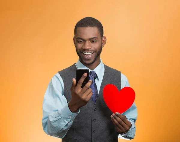 Man checking his smart phone, holding red heart — Stock Photo, Image