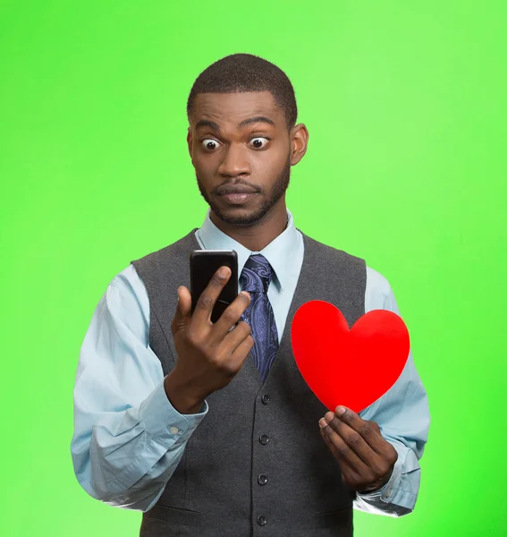 Sorprendido joven con el teléfono inteligente y el corazón rojo —  Fotos de Stock