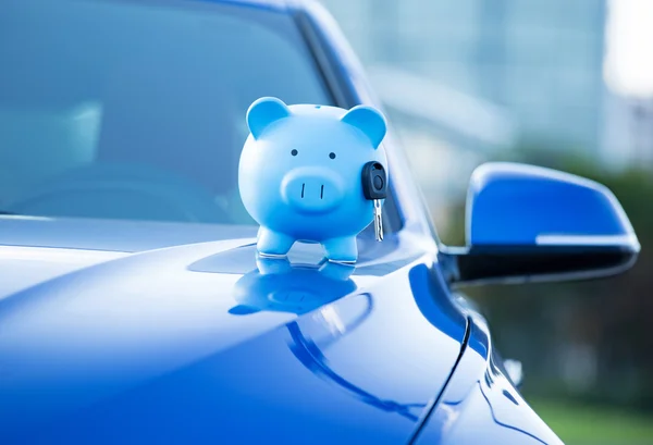 Piggy bank and key on a car hood — Stock Photo, Image