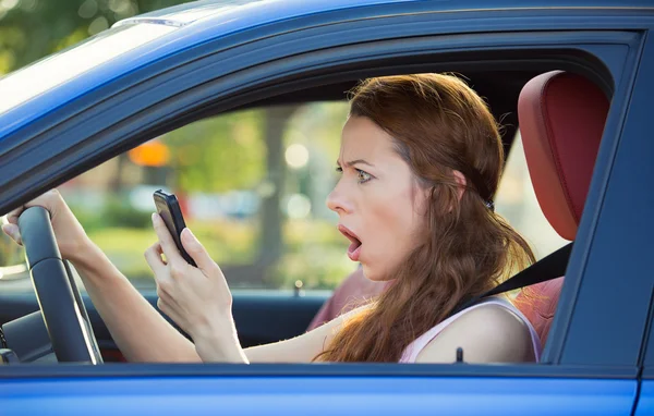 Conductora vestida, conduciendo en coche comprobando el teléfono inteligente — Foto de Stock